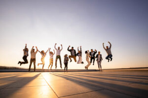 Group of people jumping into the air with the sunset behind them